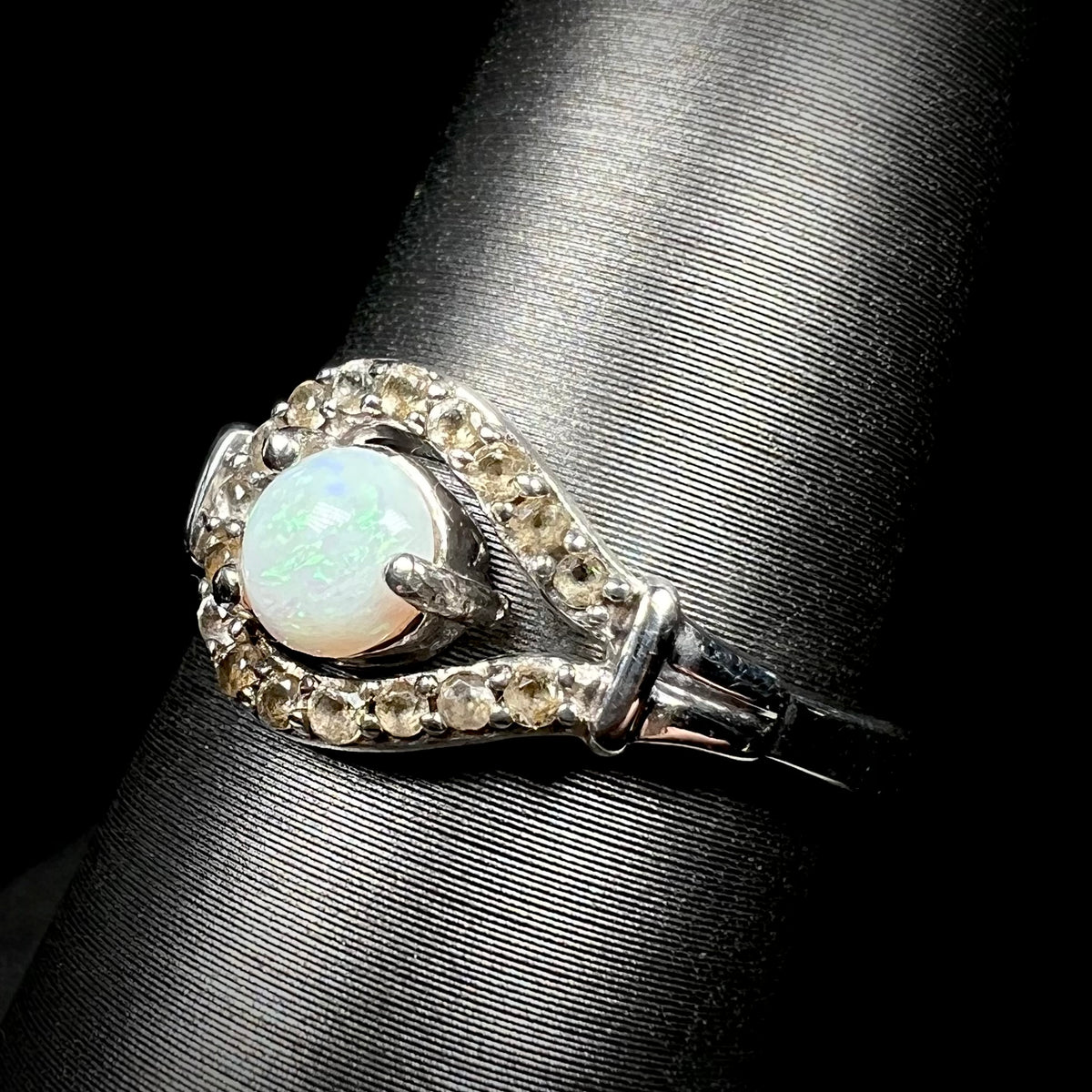 Angled close-up of Australian opal and smoky quartz ring in sterling silver, shown on ring display