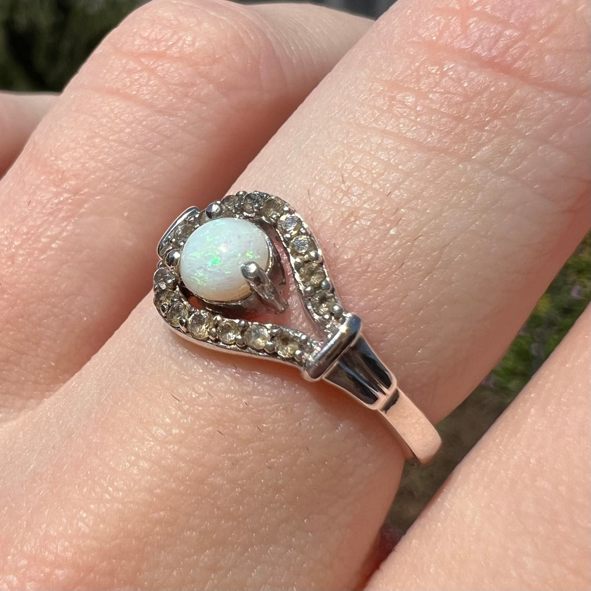 Smoky quartz accents of silver opal ring in focus, worn on finger and shown from angle in natural light