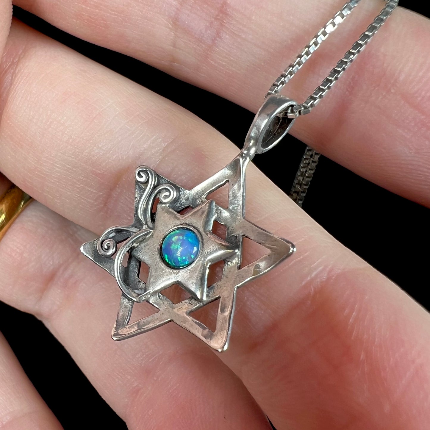 A sterling silver Star of David necklace set with a round blue lab-created opal.
