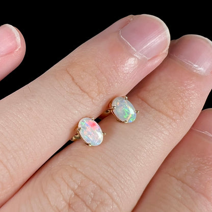 Angled view of crystal opal earrings with enhanced pink and green flashes.