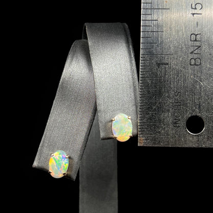 White opal stud earrings next to a ruler for size comparison, measuring approximately a third of an inch.