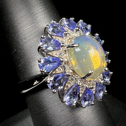 A silver opal and tanzanite halo ring shown at an angle against a black backdrop.