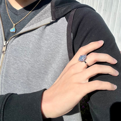 A sterling silver floating-style ring mounted with a black opal triplet in a halo of tanzanite stones.