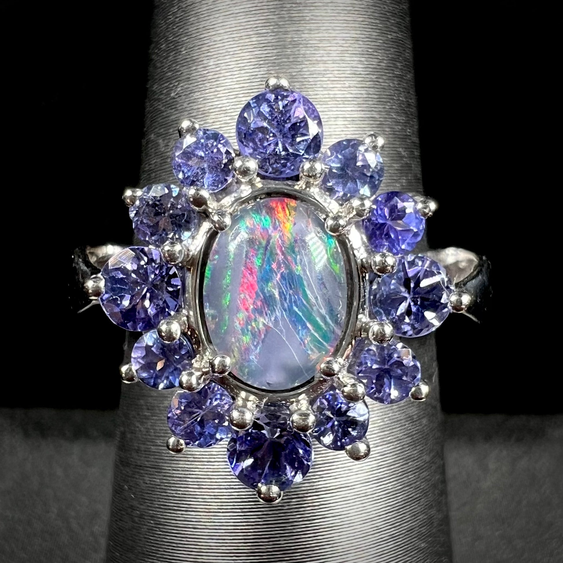 A sterling silver ring mounted with an opal triplet in a halo of tanzanites.