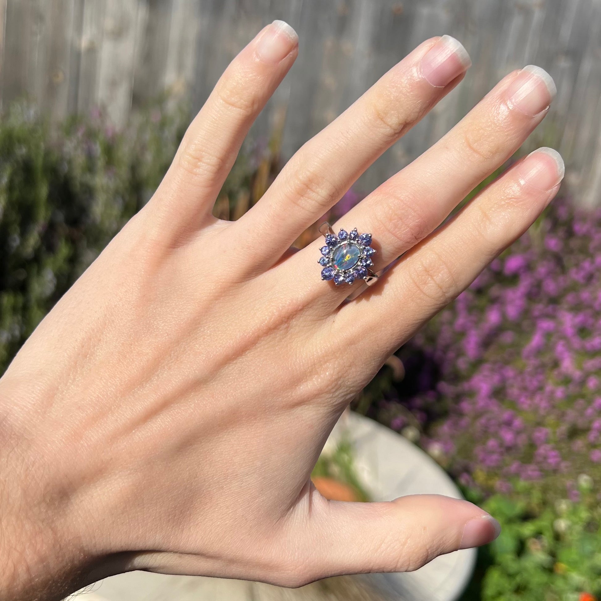 A sterling silver floating-style ring mounted with a black opal triplet in a halo of tanzanite stones.