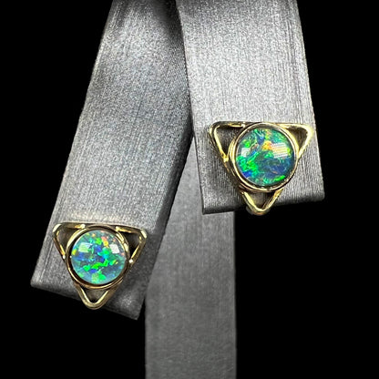A pair of triangle shaped 18k yellow gold opal stud earrings, shown from the front view.