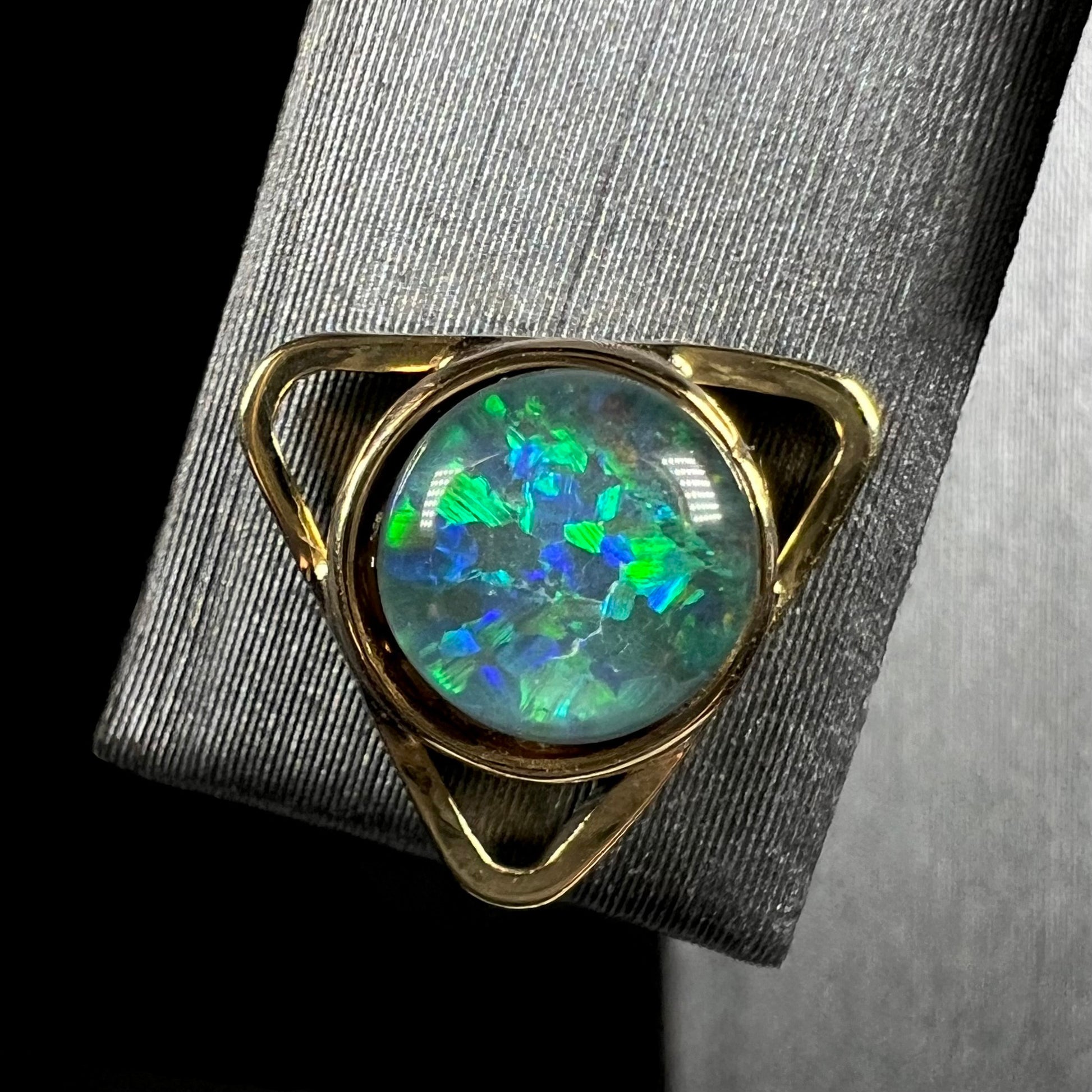 A single 18k yellow gold opal triplet earring shown close-up.  A gap is seen between the round opal and the bezel.