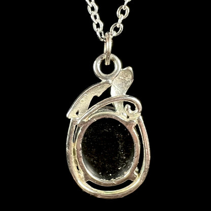 Back side of base metal opal triplet pendant on chain; the pendant's open back shows opal's black backing
