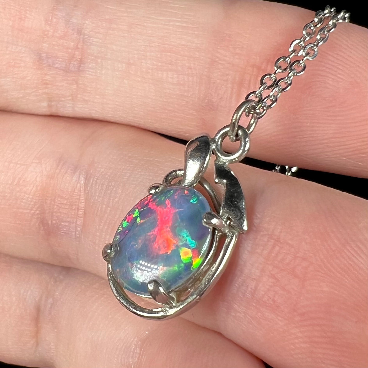 Bright red flash seen in opal triplet pendant, shown close-up in hand from angle