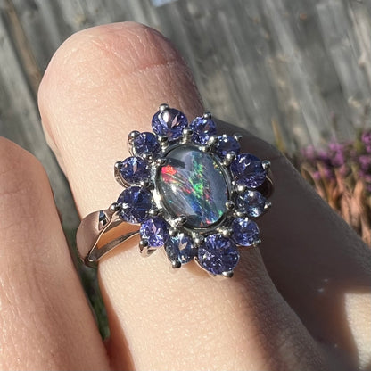 A sterling silver floating-style ring mounted with a black opal triplet in a halo of tanzanite stones.