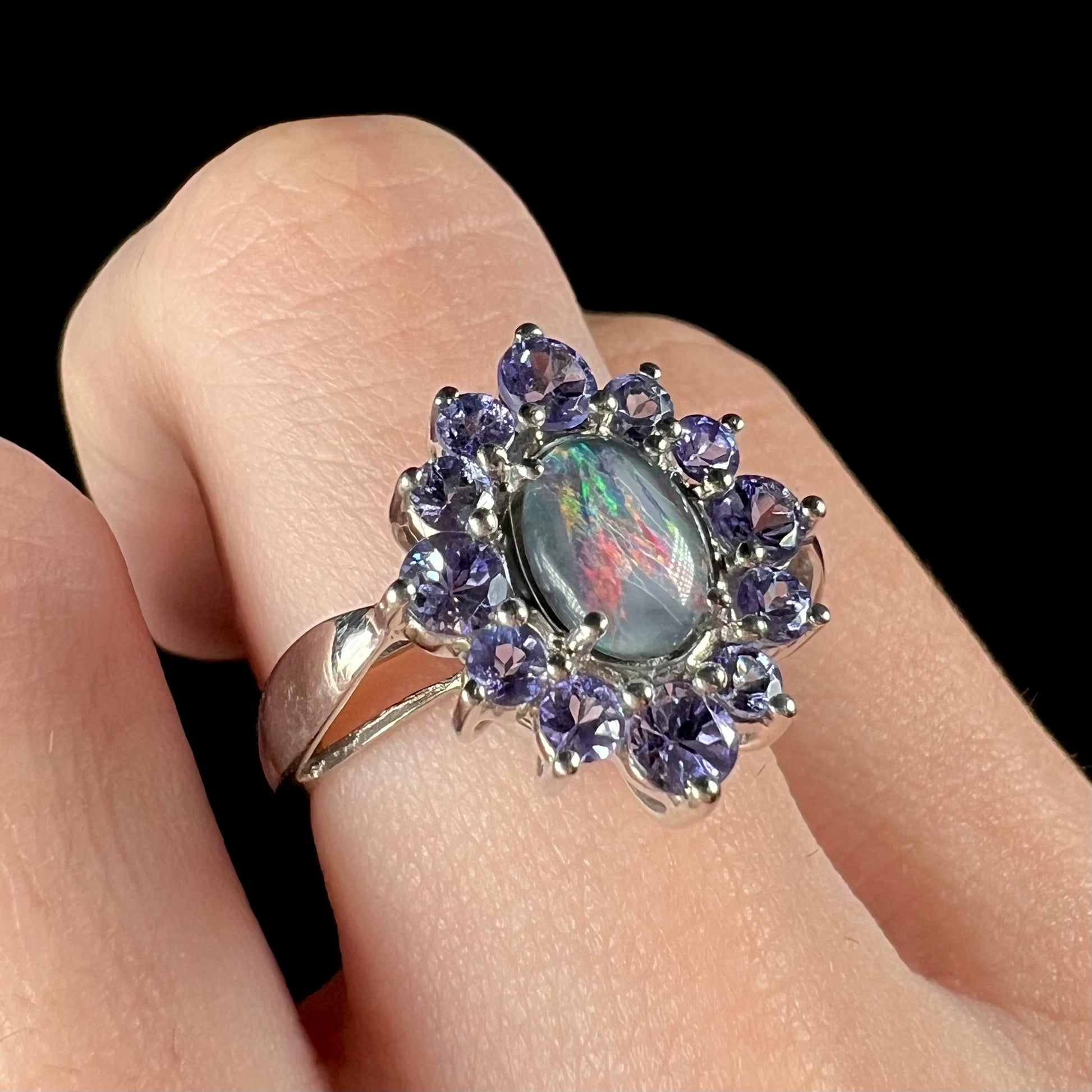 A sterling silver floating-style ring mounted with a black opal triplet in a halo of tanzanite stones.