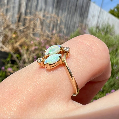 A ladies' gold ring mounted with two marquise cut opals and two diamond accents.