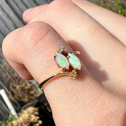 A ladies' gold ring mounted with two marquise cut opals and two diamond accents.