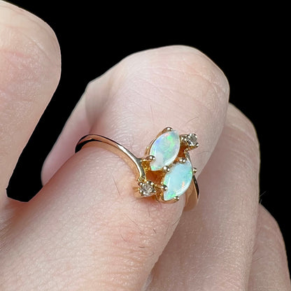 A ladies' gold ring mounted with two marquise cut opals and two diamond accents.