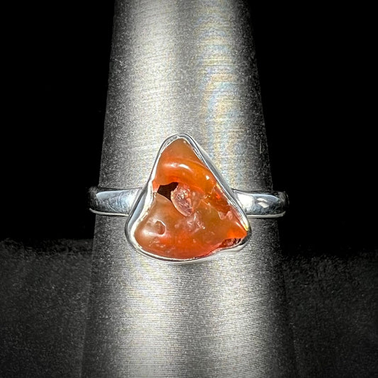 A polished fire opal crystal bezel set into a sterling silver ring.  The opal is an orange color.