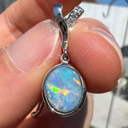 An oval cut black opal doublet necklace set in sterling silver with white zircon accent stones.