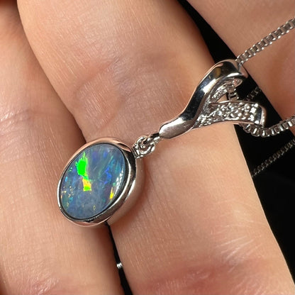 A sterling silver necklace set with a natural black opal doublet and white zircon accent stones.