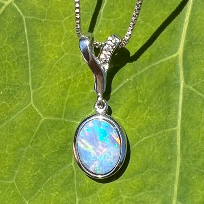 An oval cut black opal doublet necklace set in sterling silver with white zircon accent stones.