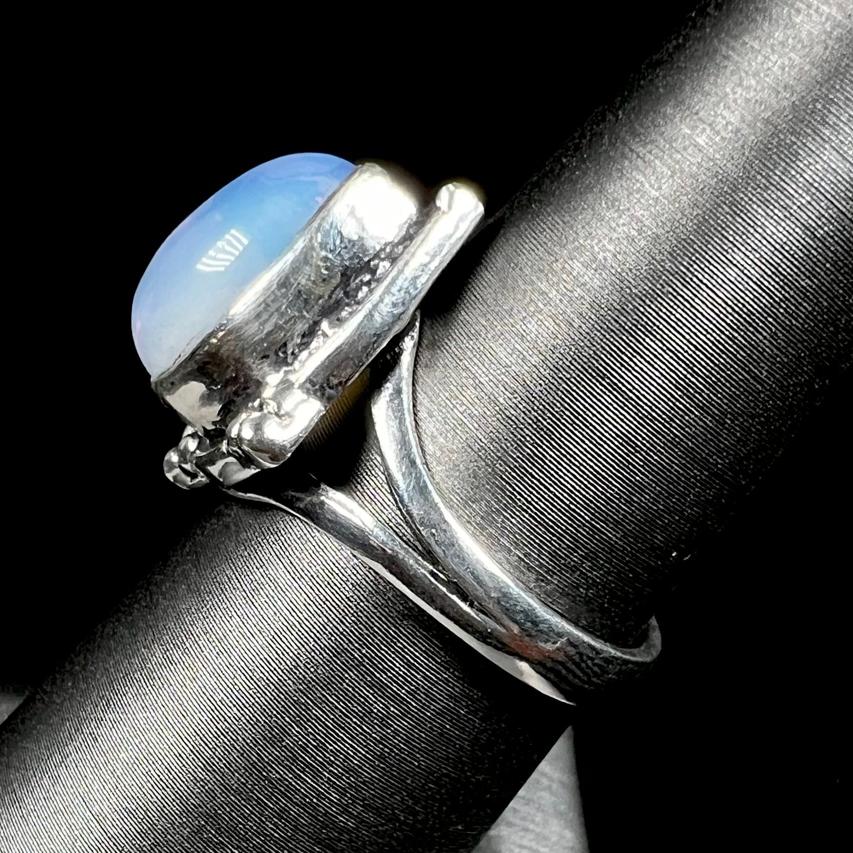 A handmade white metal ring set with a pear shaped opalite cabochon.