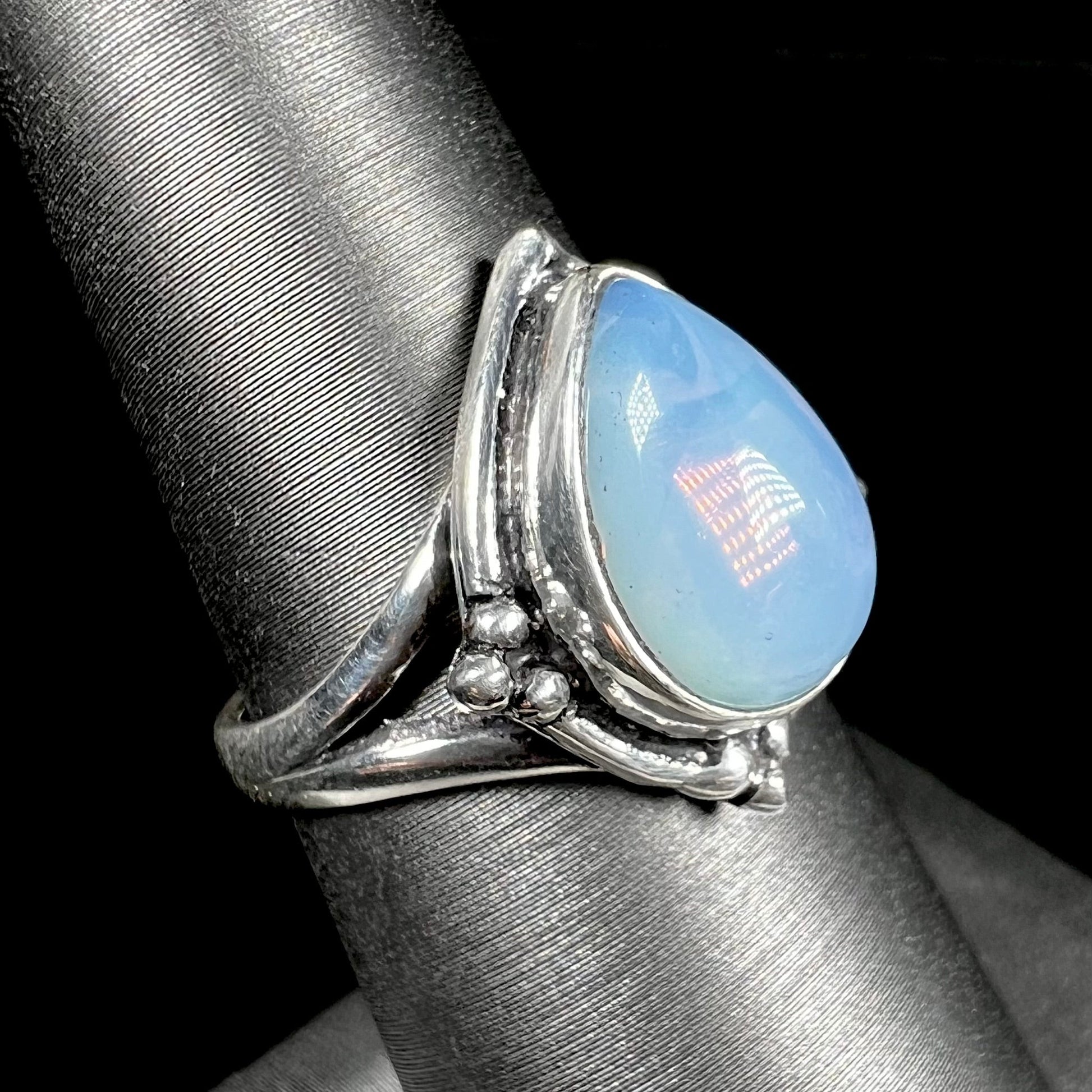 A handmade white metal ring set with a pear shaped opalite cabochon.