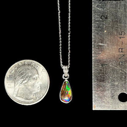 A natural, pear shaped Australian boulder opal with blue, purple, and green colors bezel set into a sterling silver necklace.
