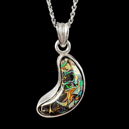 A sterling silver necklace bezel set with a natural Koroit boulder opal stone.  The stone is shaped like a crescent moon.