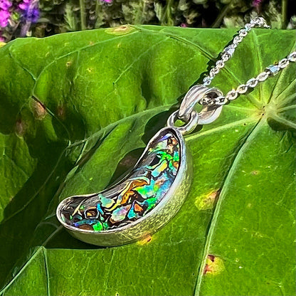 A sterling silver necklace set with a natural Koroit boulder opal shaped like a crescent moon.