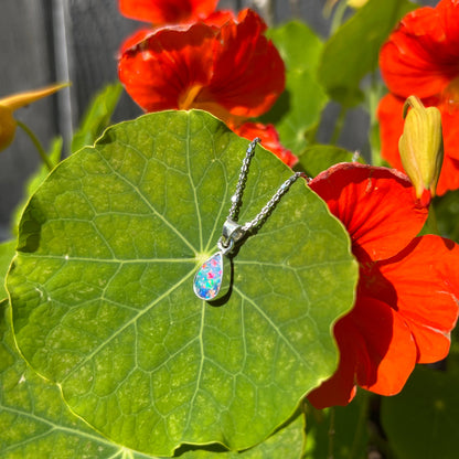 A pear shaped black opal necklace set in sterling silver.  The opal vividly flashes every color of the rainbow.