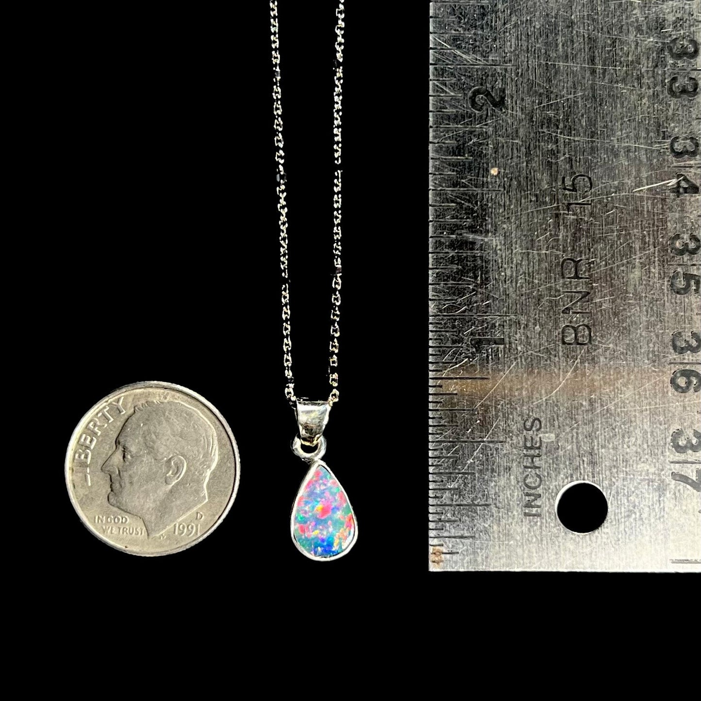 A pear shaped black opal necklace set in sterling silver.  The opal vividly flashes every color of the rainbow.