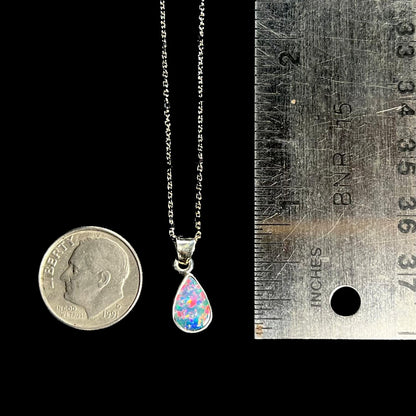 A pear shaped black opal necklace set in sterling silver.  The opal vividly flashes every color of the rainbow.
