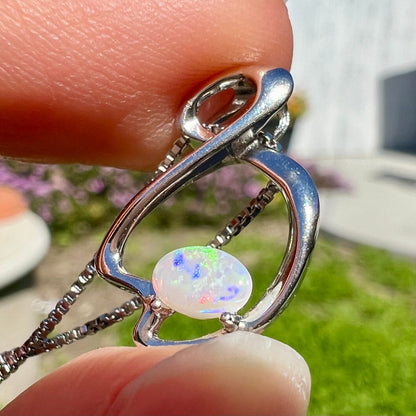 A ladies' sterling silver necklace set with an oval cabochon cut natural white crystal opal with green fire.