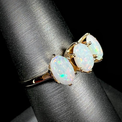 A vintage yellow gold ring mounted with three oval cut white Australian opals.