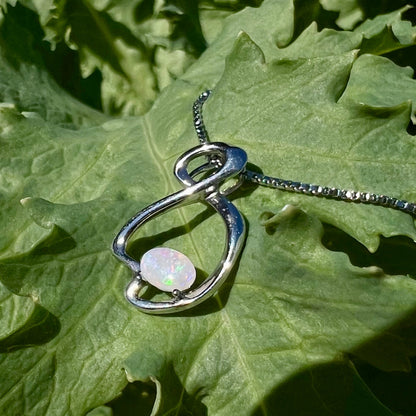A ladies' sterling silver necklace set with an oval cabochon cut natural white crystal opal with green fire.