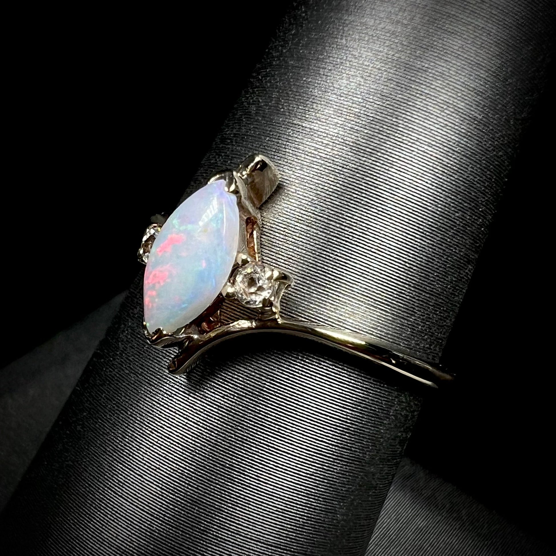 A yellow gold marquise cut opal ring set with two white sapphire accent stones.