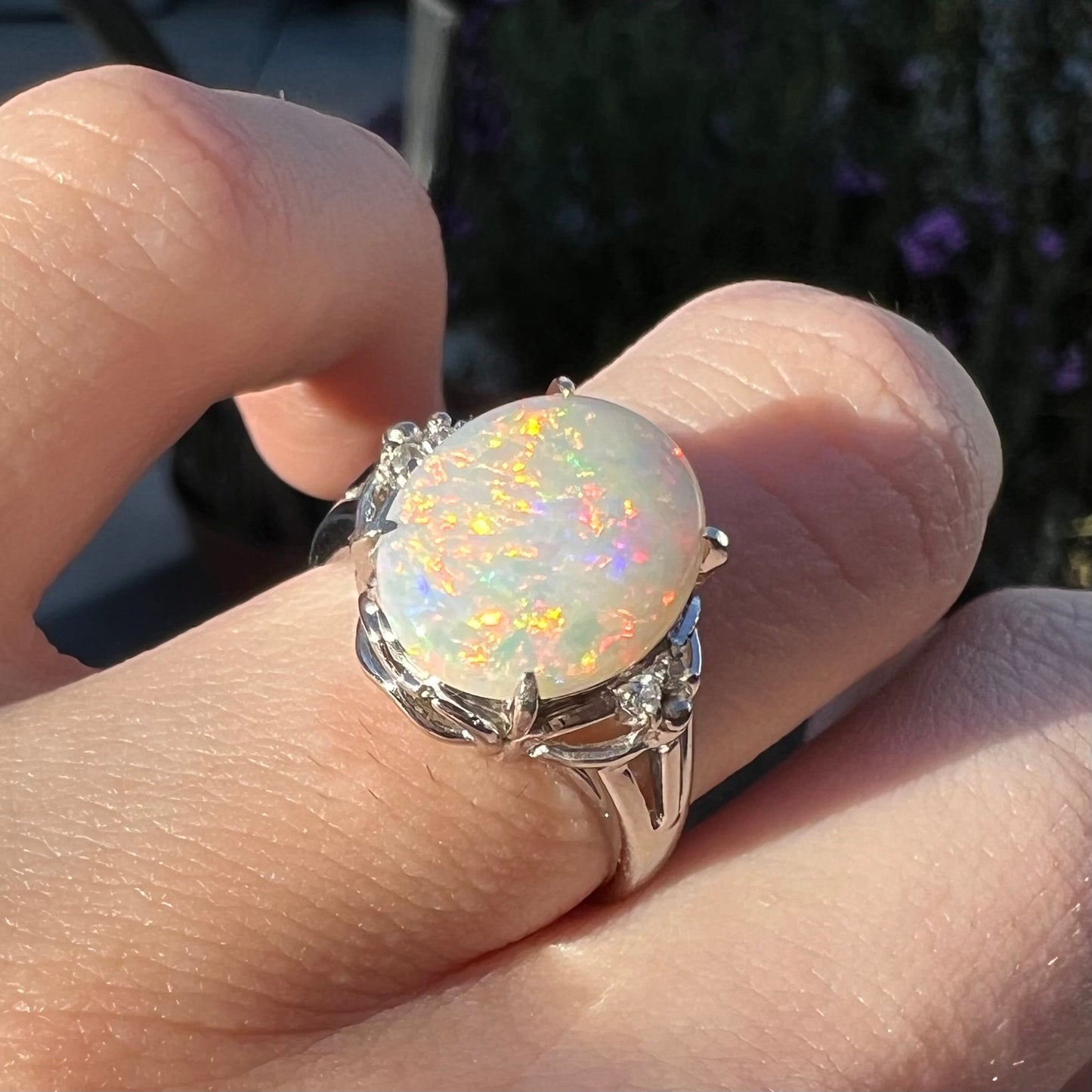 A 2.36ct orange Australian opal mounted in a platinum ring with diamond accents, worn in the sun.