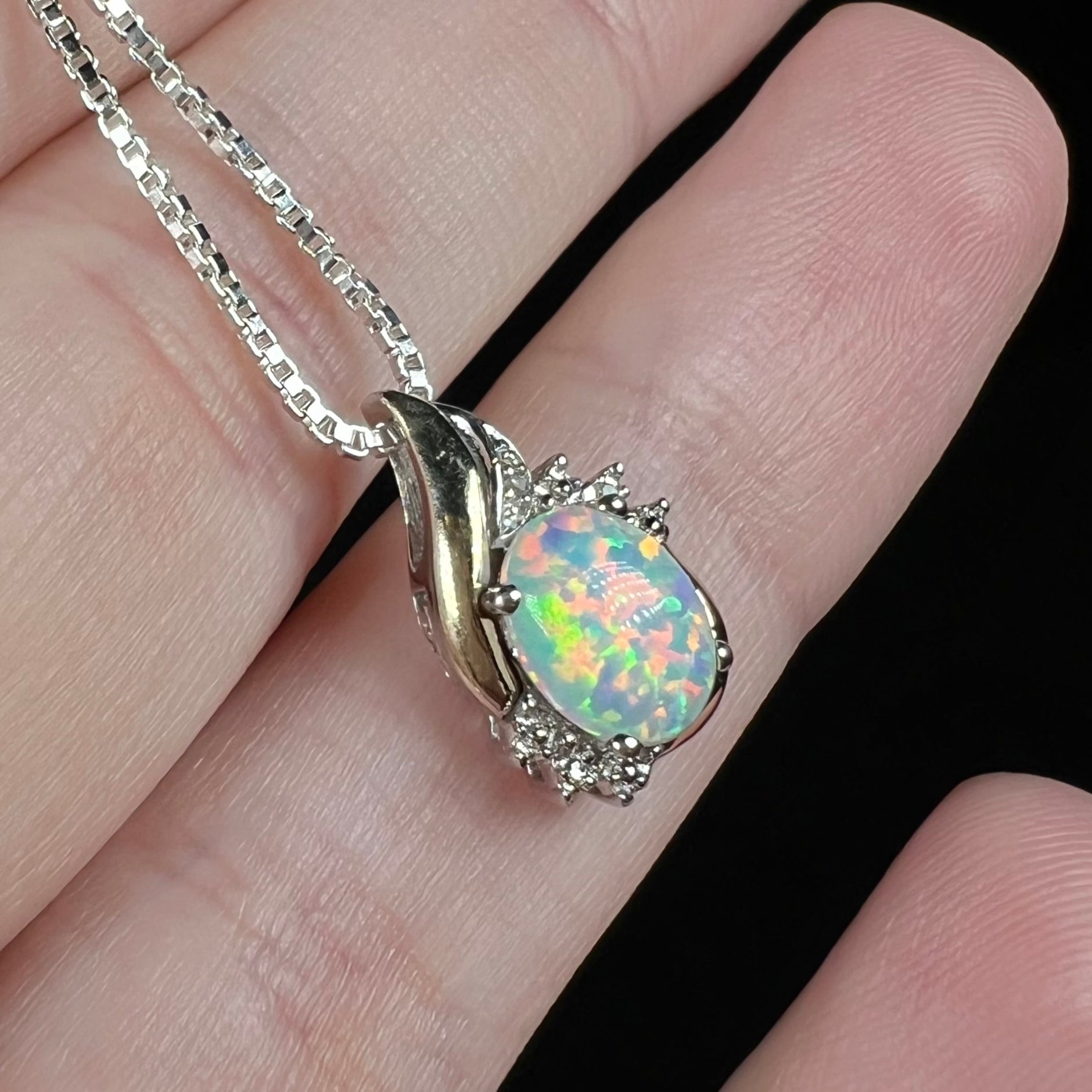 A sterling silver and 10k gold pendant set with a lab-created opal with orange and green fire.