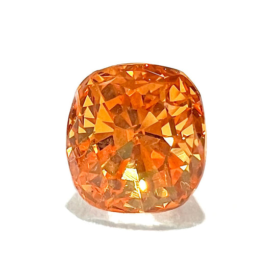 A faceted cushion cut natural orange sapphire gemstone.  The stone is cut to enhance the orange color.