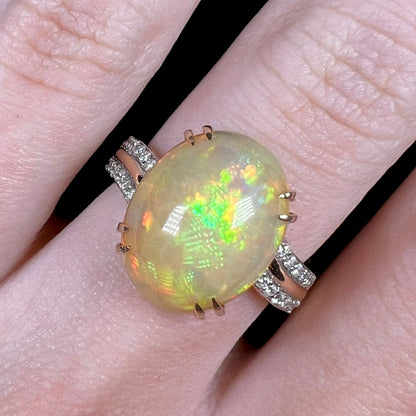 Close-up of oval cabochon cut Ethiopian opal and diamond ring, worn on finger