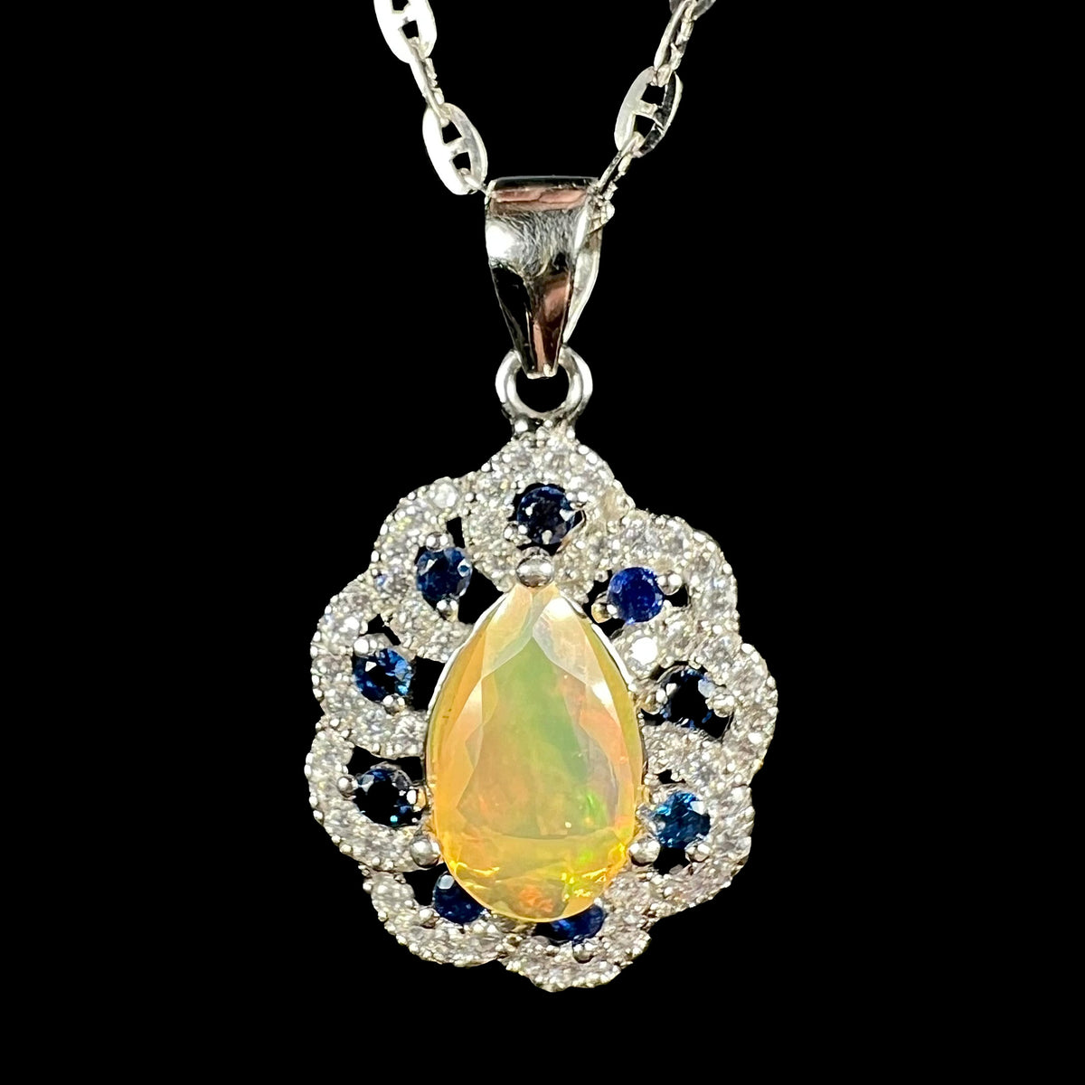 Close-up of women's sterling silver pear shaped Ethiopian opal, blue sapphire, and CZ necklace