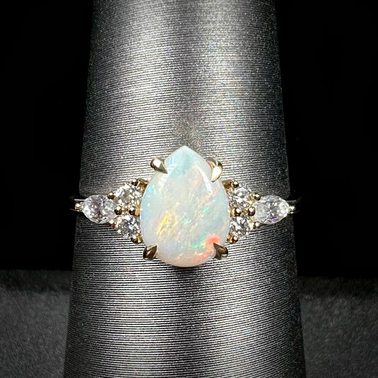 A dainty, pear shaped opal ring mounted in yellow gold with moissanite accents.