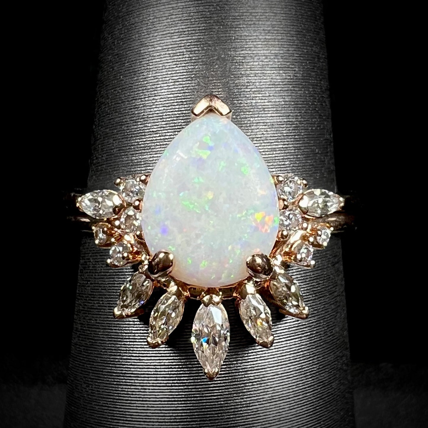 Close-up of women's pear shaped Australian opal and moissanite wedding ring set in 14k rose gold on ring display