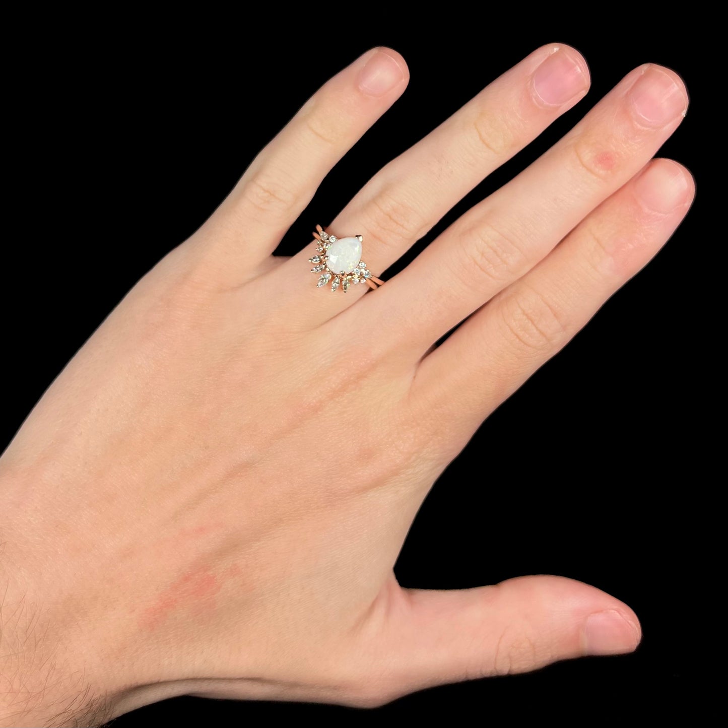 Pear shaped Australian opal wedding ring set with moissanite accents in rose gold on hand