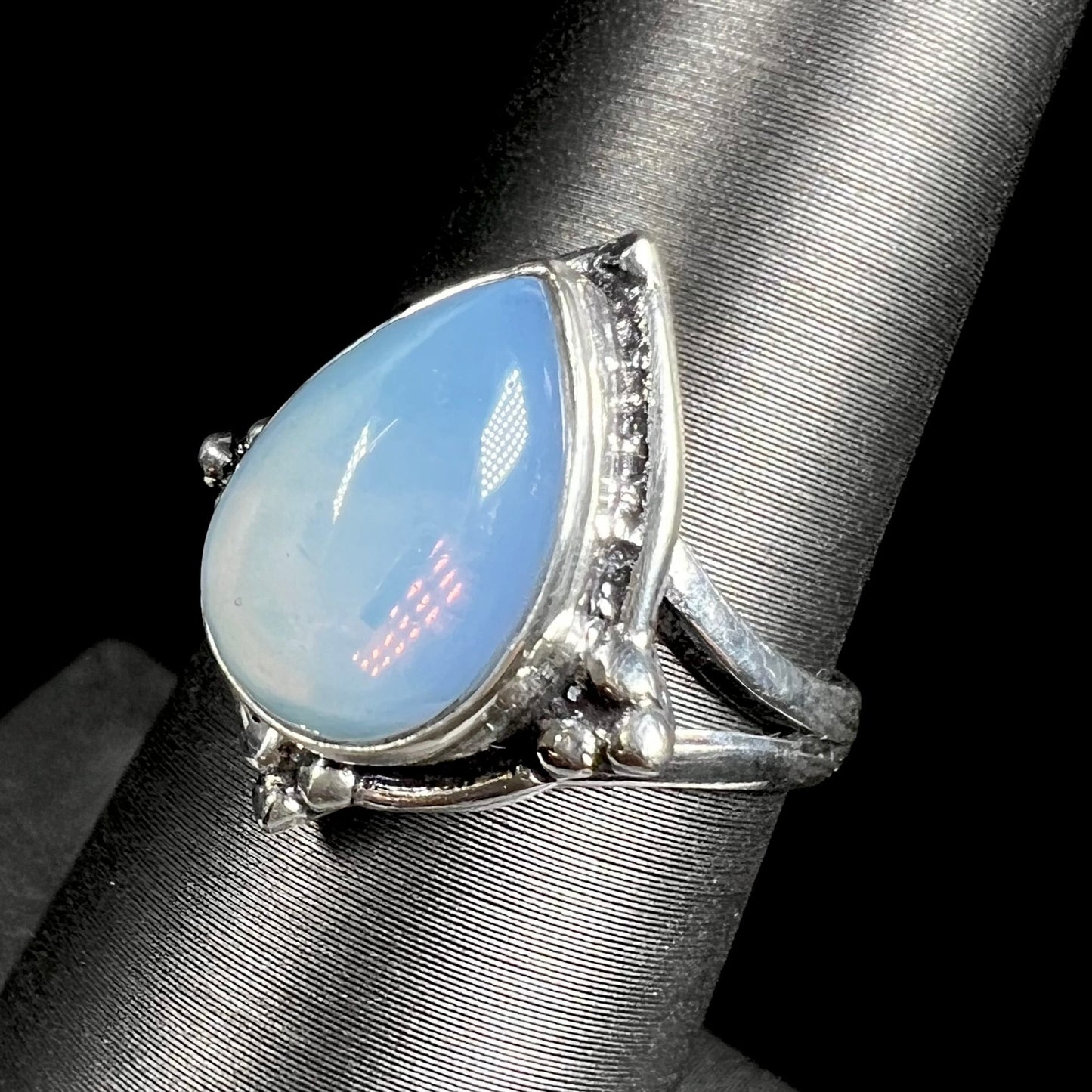 A handmade white metal ring set with a pear shaped opalite cabochon.