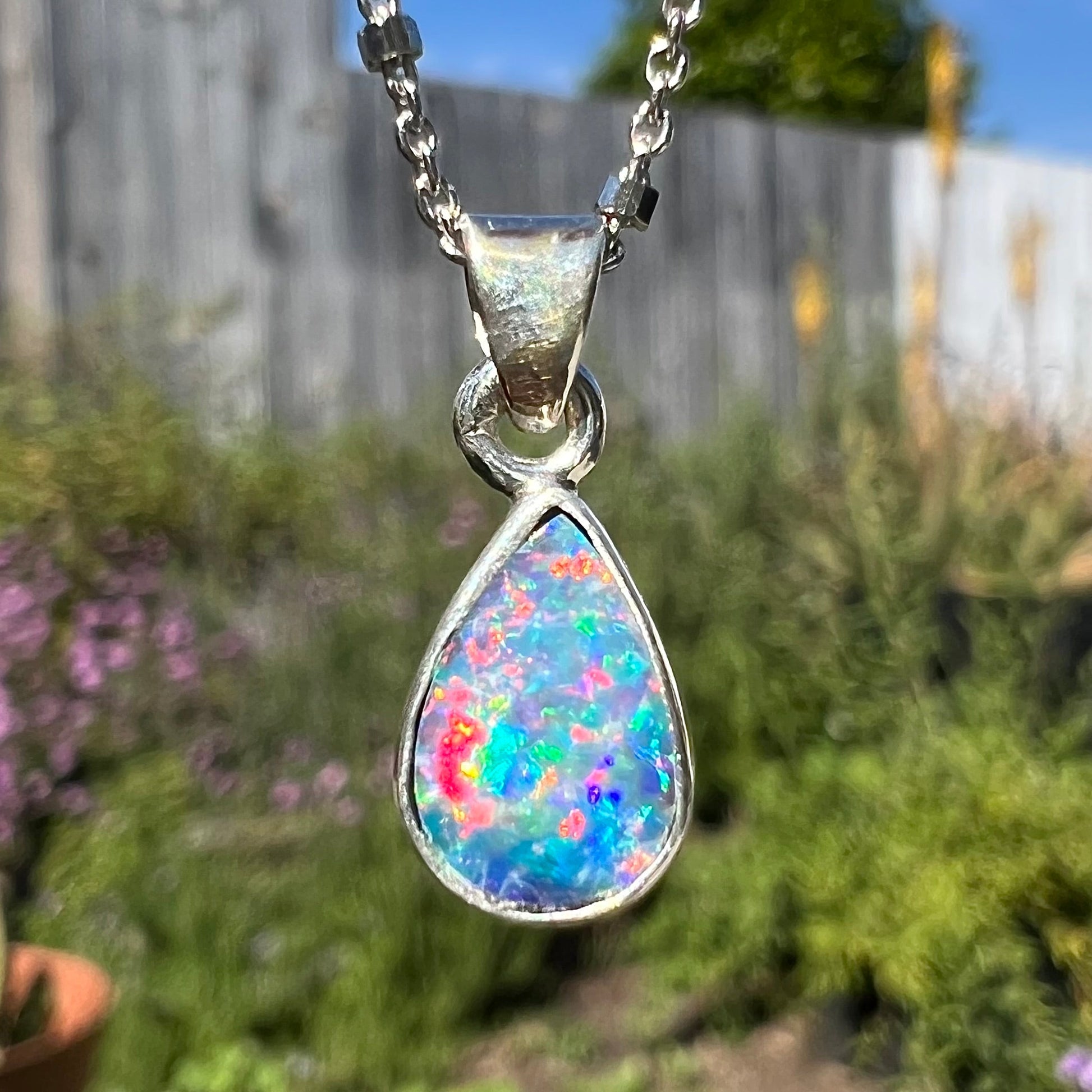 A pear shaped black opal necklace set in sterling silver.  The opal vividly flashes every color of the rainbow.