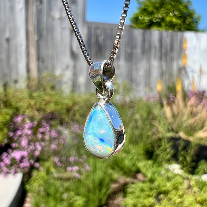 A dainty, sterling silver necklace bezel set with a natural, pear shaped opal stone.