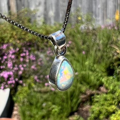 A dainty, sterling silver necklace bezel set with a natural, pear shaped opal stone.