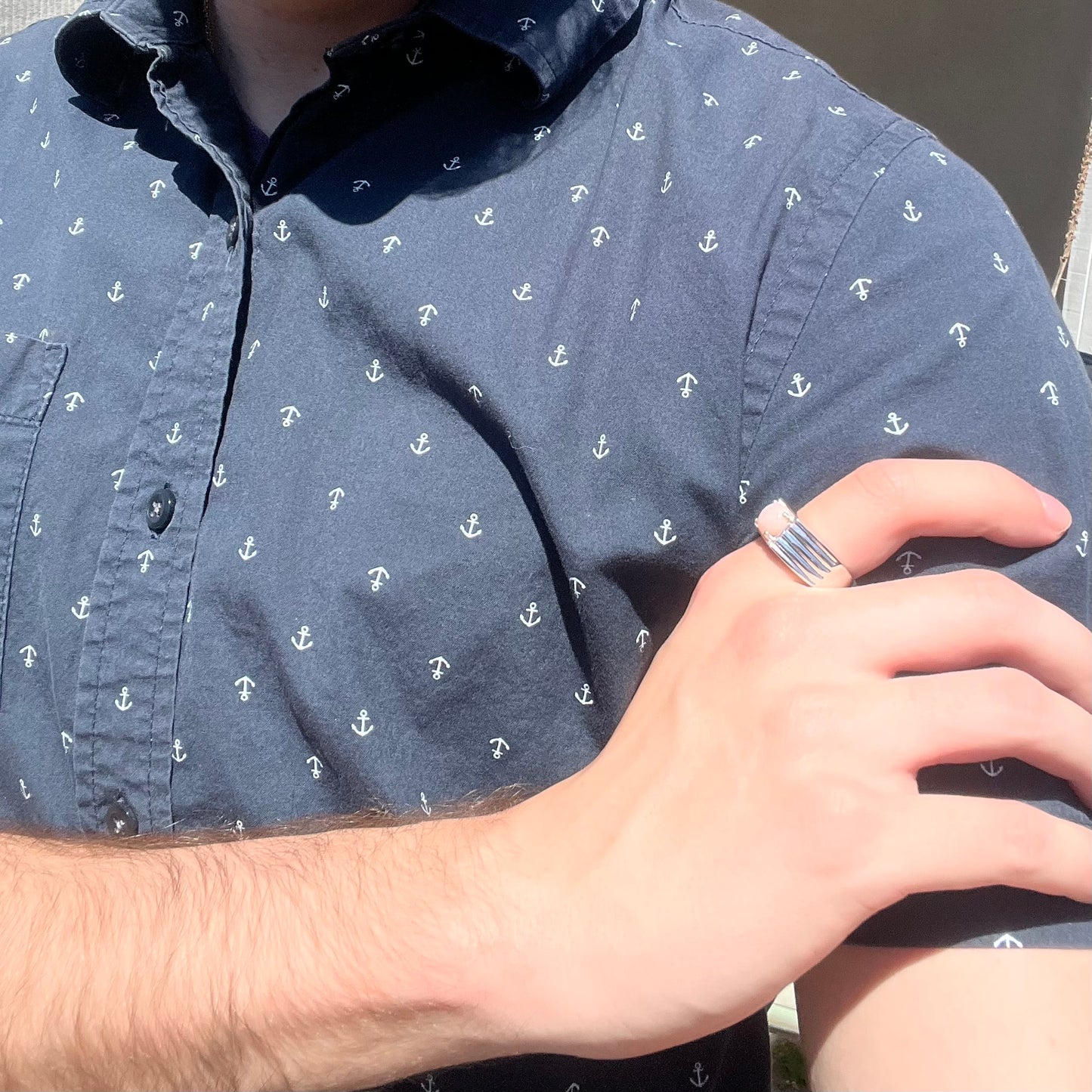 Man resting hand on shoulder while wearing sterling silver pink Peruvian opal men's ring in sunlight