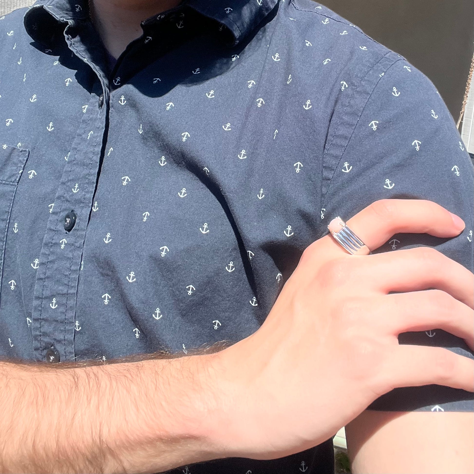Man resting hand on shoulder while wearing sterling silver pink Peruvian opal men's ring in sunlight