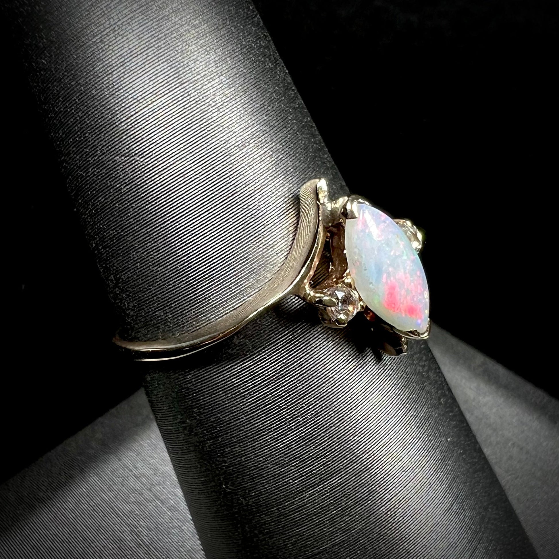 A yellow gold marquise cut opal ring set with two white sapphire accent stones.