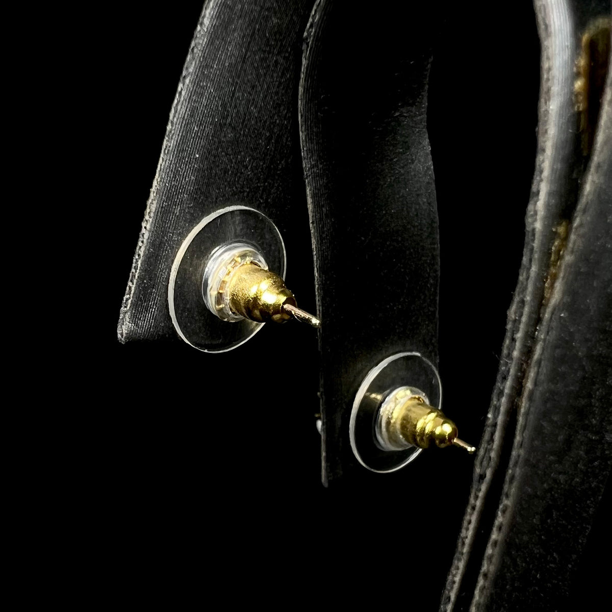 Pair of plastic disc earring backs with gold plated posts on earring display